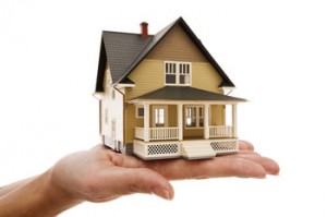 a person holding a tiny model house in his/her hand